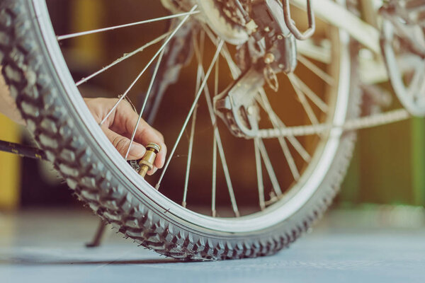 Close-up of a young man prepare to pumping the old bicycle wheel in his home. .