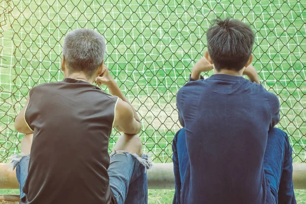 Back view of male parents cheering their childrens playing football in school. — Stock Photo, Image