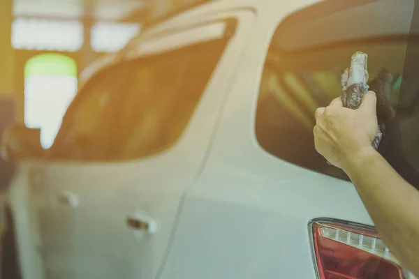 Close up to hand of male worker use wet newspapers to clean the glass part of the car. Selective focus on hand. — Stock Photo, Image