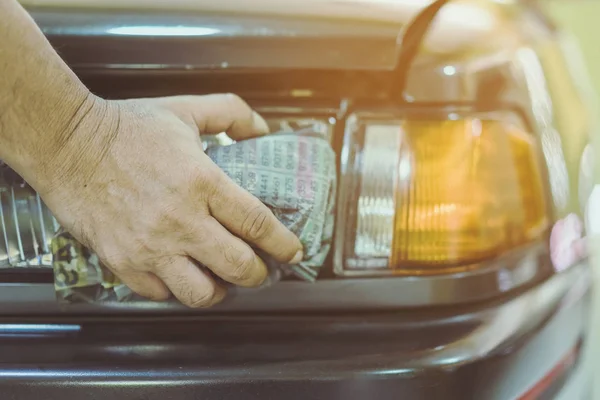 Close up to hand of male worker use wet newspapers to clean the glass part of the car. Selective focus on hand. — Stock Photo, Image