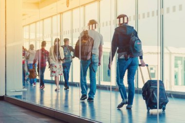 Terminalden uçağa giden uçakta yürüyen yolcuların ve seyahat eden bagajların geri görünümü.