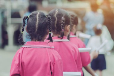 Küçük kızların arka planı uzun ponpon kızlar yerine kağıt rulo kullanıyor. Okul yürüyüşü için sopa kullanıyor..