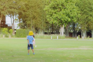 Mavi gömlekli küçük bir çocuk akşamları parktaki yeşil çimenlerde oynayarak dinlendirici bir zaman sahiptir..
