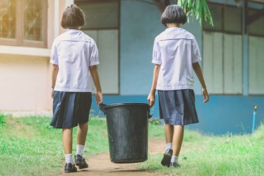 Kız Öğrenciler atık yığını için sınıftan çöp kaldırmak için yardım