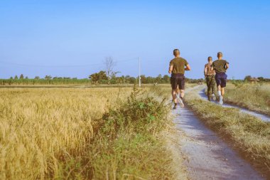 Akşamları pirinç tarlalarında birlikte koşan ve arkadaşlarıyla egzersiz yapan erkeklerin arka planı..
