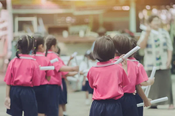Vista posterior de las niñas usan rollos de papel en lugar de largos bastones de porrista para la práctica de marcha del desfile escolar — Foto de Stock