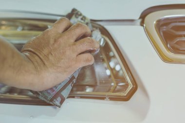 Erkek işçiye yakın mesafede, arabanın cam kısmını temizlemek için ıslak gazeteler kullanın. Eldeki seçici odaklanma.