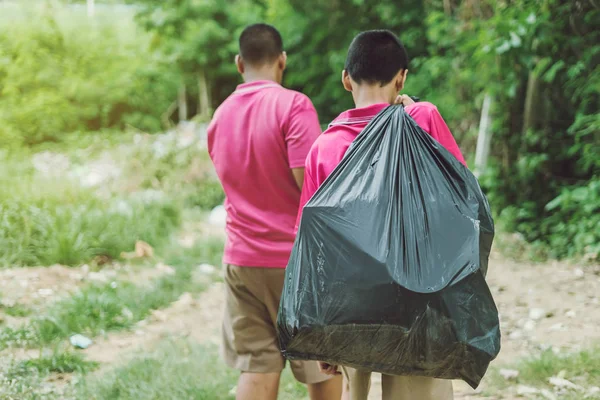 Los estudiantes masculinos ayudan a eliminar la basura del aula para amontonar los desechos. Enfoque selectivo en bolsa de basura negra . — Foto de Stock