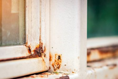 Çerçevenin köşesindeki eski beyaz demir pencerenin pasını kapat. Arkaplanı bulanık.