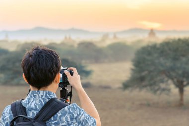 Asya tarihi mirası şehir Bagan, Myanmar'da antik pagoda tapınaklarında güneş batarken turistlerin arka görünümü hayranlık ve fotoğraf çekmek