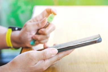 Corona virüsü (Covid-19) enfeksiyonunu önlemek için akıllı telefonu alkol spreyiyle temizleyen kadının elleri, uzun süre boyunca mobil ekran koruyucusu filminin bozulmasına yol açtı. Seçici odak.