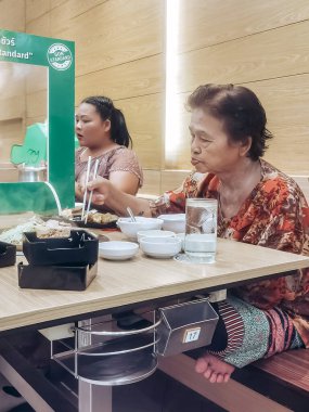 KANCHANABURI, THAILAND-JUNE 12020: Corona virüsünün (Covid-19) Robinson mağazasındaki Barbekü Plaza restoranında yayılmasını önlemek için sosyal mesafeli yemek.