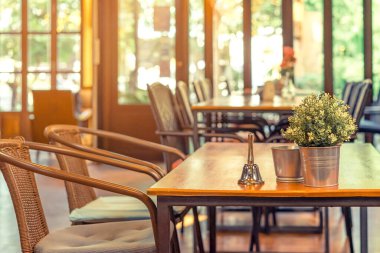 Garsonu aramak için küçük bir zil ve kahve dükkanındaki bir masanın üzerine yerleştirilmiş alüminyum bir kazanda suni çiçekler..