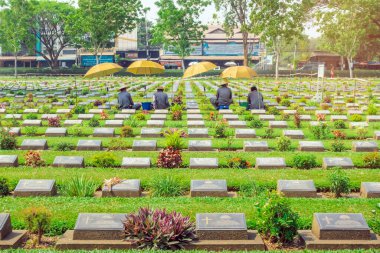 KANCHANABURI THAILAND - 21 Şubat: Kimliği belirsiz işçiler, 21 Şubat 2020 'de Kanchanaburi, Tayland' daki Kanchanaburi Müttefik Savaş Mezarlığı 'nda çiçek yenileyip dekore ediyorlar