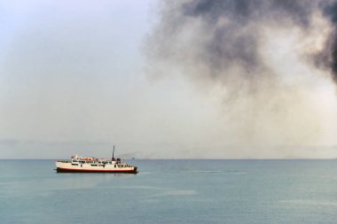 Siyah dumanlı feribot egzoz borusu ve arka planda bulutlarla gökyüzü. Hava kirliliği.
