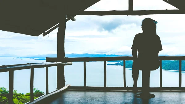 Back view of woman enjoy with beautiful scenery view of nature with a large reservoir above the Srinagarind Dam at Rai Ya Yam view point in Si Sawat District, Kanchanaburi Thailand.