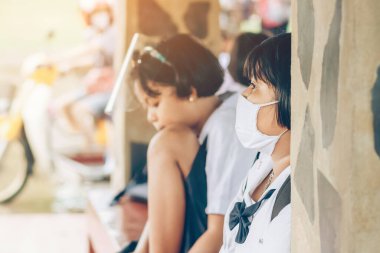 Kanchanaburi, Tayland-2 Temmuz 2020: Coronavirus 'un (Covid-19) okuldan sonra eve dönmesini engellemek için tanımlanamayan ilkokul öğrencileri maske takıyor ve KTR okulunda yağmur sadece duruyor.