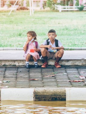 Kanchanaburi, Tayland-2 Temmuz 2020: Coronavirus 'un (Covid-19) okuldan sonra eve dönmesini engellemek için tanımlanamayan ilkokul öğrencileri maske takıyor ve KTR okulunda yağmur sadece duruyor.