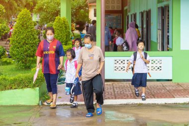 Kanchanaburi, Tayland-2 Temmuz 2020: Taylandlı öğrenciler okuldan sonra kendilerini Coronavirus 'tan (Covid-19) korumak ve KTR okulunda yağmur durduktan sonra evlerine dönmek için çeşitli tıbbi maskeler takıyorlar.