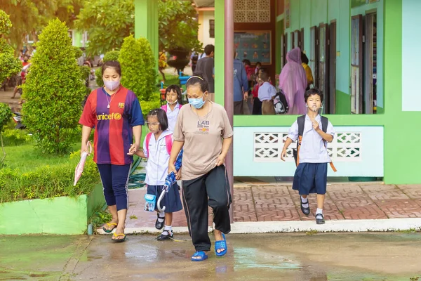 Kanchanaburi, Tayland-2 Temmuz 2020: Taylandlı öğrenciler okuldan sonra kendilerini Coronavirus 'tan (Covid-19) korumak ve KTR okulunda yağmur durduktan sonra evlerine dönmek için çeşitli tıbbi maskeler takıyorlar.