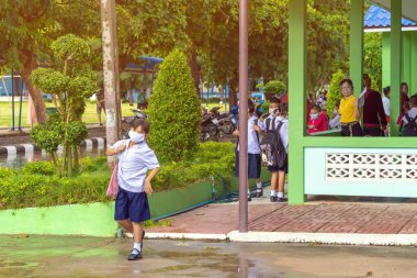 Kanchanaburi, Tayland-2 Temmuz 2020: Taylandlı öğrenciler okuldan sonra kendilerini Coronavirus 'tan (Covid-19) korumak ve KTR okulunda yağmur durduktan sonra evlerine dönmek için çeşitli tıbbi maskeler takıyorlar.