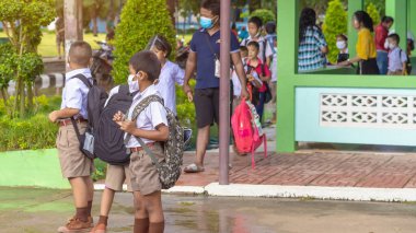 Kanchanaburi, Tayland-2 Temmuz 2020: Taylandlı öğrenciler okuldan sonra kendilerini Coronavirus 'tan (Covid-19) korumak ve KTR okulunda yağmur durduktan sonra evlerine dönmek için çeşitli tıbbi maskeler takıyorlar.