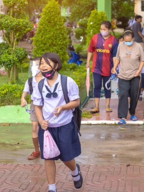 Kanchanaburi, Tayland-2 Temmuz 2020: Taylandlı öğrenciler okuldan sonra kendilerini Coronavirus 'tan (Covid-19) korumak ve KTR okulunda yağmur durduktan sonra evlerine dönmek için çeşitli tıbbi maskeler takıyorlar.