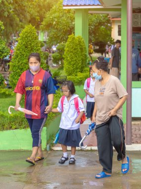 Kanchanaburi, Tayland-2 Temmuz 2020: Taylandlı öğrenciler okuldan sonra kendilerini Coronavirus 'tan (Covid-19) korumak ve KTR okulunda yağmur durduktan sonra evlerine dönmek için çeşitli tıbbi maskeler takıyorlar.