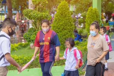 Kanchanaburi, Tayland-2 Temmuz 2020: Taylandlı öğrenciler okuldan sonra kendilerini Coronavirus 'tan (Covid-19) korumak ve KTR okulunda yağmur durduktan sonra evlerine dönmek için çeşitli tıbbi maskeler takıyorlar.
