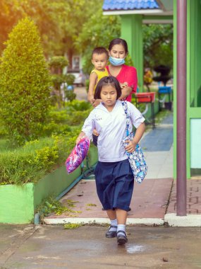 Kanchanaburi, Tayland-2 Temmuz 2020: Taylandlı öğrenciler okuldan sonra kendilerini Coronavirus 'tan (Covid-19) korumak ve KTR okulunda yağmur durduktan sonra evlerine dönmek için çeşitli tıbbi maskeler takıyorlar.