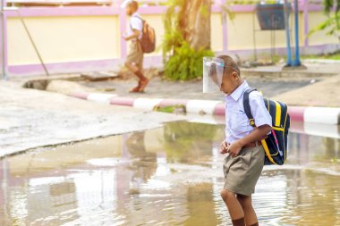Kanchanaburi, Tayland-2 Temmuz 2020: Taylandlı öğrenciler okuldan sonra kendilerini Coronavirus 'tan (Covid-19) korumak ve KTR okulunda yağmur durduktan sonra evlerine dönmek için çeşitli tıbbi maskeler takıyorlar.