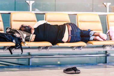 Havaalanı terminalinde yolcu beklerken banklarda kestirirken yorgun düşmüş..