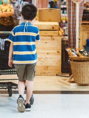 Corona Virüsü 'nün (Covid-19) süpermarketten alışveriş yapmasını önlemek için yüz maskesi takan çocuğun arka plan görüntüsü. Marketteki virüs salgını sırasında alışveriş arabalı bir çocuk. Yeni normal yaşam tarzı.