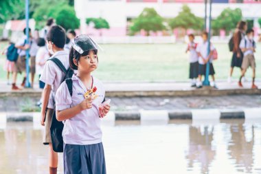 Kanchanaburi, Tayland-2 Temmuz 2020: Coronavirus 'un (Covid-19) okuldan sonra eve dönmesini engellemek için tanımlanamayan ilkokul öğrencileri maske takıyor ve KTR okulunda yağmur sadece duruyor.
