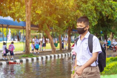 Kanchanaburi, Tayland-2 Temmuz 2020: Taylandlı öğrenciler okuldan sonra kendilerini Coronavirus 'tan (Covid-19) korumak ve KTR okulunda yağmur durduktan sonra evlerine dönmek için çeşitli tıbbi maskeler takıyorlar.