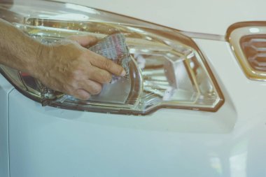 Erkek işçiye yakın mesafede, arabanın cam kısmını temizlemek için ıslak gazeteler kullanın. Eldeki seçici odaklanma.