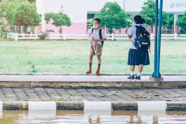 Kanchanaburi, Tayland-2 Temmuz 2020: Coronavirus 'un (Covid-19) okuldan sonra eve dönmesini engellemek için tanımlanamayan ilkokul öğrencileri maske takıyor ve KTR okulunda yağmur sadece duruyor.