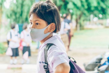 Kanchanaburi, Tayland-2 Temmuz 2020: Coronavirus 'un (Covid-19) okuldan sonra eve dönmesini engellemek için tanımlanamayan ilkokul öğrencileri maske takıyor ve KTR okulunda yağmur sadece duruyor.