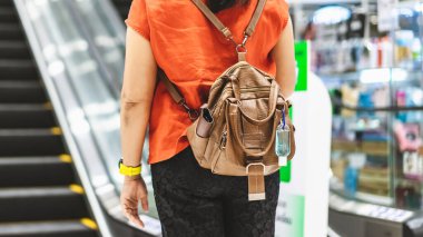 Corona Virüsü 'nü (Covid-19) öldürmek için mini taşınabilir alkol jeli şişesi alışveriş merkezine alışverişe giden bir kadının deri omuz çantasına asılır. Yeni normal yaşam tarzı. Alkol jeline odaklan