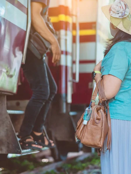 Corona Virüsü 'nü (Covid-19) öldürmek için mini taşınabilir alkol jeli şişesi demiryolu istasyonundaki kadının deri omuz çantasına asıldı. Yeni normal yaşam tarzı. Sağlık hizmeti konsepti. Alkol jeline odaklan