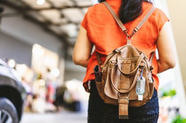 Corona Virüsü 'nü (Covid-19) öldürmek için mini taşınabilir alkol jeli şişesi alışveriş merkezine alışverişe giden bir kadının deri omuz çantasına asılır. Yeni normal yaşam tarzı. Alkol jeline odaklan