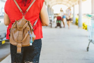 Corona Virüsü 'nü (Covid-19) öldürmek için mini taşınabilir alkol jeli şişesi bir kadının deri omuz çantasına asılıp alışveriş merkezine gider. Yeni normal yaşam tarzı. Alkol jeline odaklan