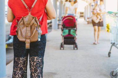 Corona Virüsü 'nü (Covid-19) öldürmek için mini taşınabilir alkol jeli şişesi bir kadının deri omuz çantasına asılıp alışveriş merkezine gider. Yeni normal yaşam tarzı. Alkol jeline odaklan