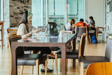 BANGKOK-THAILAND, 14 Temmuz 2020: Tanımlanamayan müşteriler akıllı telefon kullanıyor ve Chamchuri Meydanı 'ndaki True Coffee' de koltukların sosyal mesafeye ayrıldığı içecek ile rahatlıyorlar..