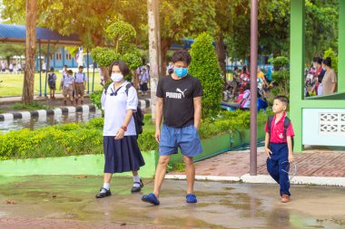 Kanchanaburi, Tayland-2 Temmuz 2020: Taylandlı öğrenciler okuldan sonra kendilerini Coronavirus 'tan (Covid-19) korumak ve KTR okulunda yağmur durduktan sonra evlerine dönmek için çeşitli tıbbi maskeler takıyorlar.