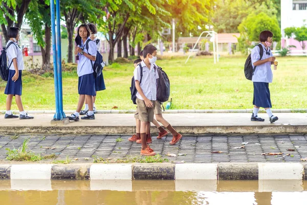 Kanchanaburi, Tayland-2 Temmuz 2020: Taylandlı öğrenciler okuldan sonra kendilerini Coronavirus 'tan (Covid-19) korumak ve KTR okulunda yağmur durduktan sonra evlerine dönmek için çeşitli tıbbi maskeler takıyorlar.