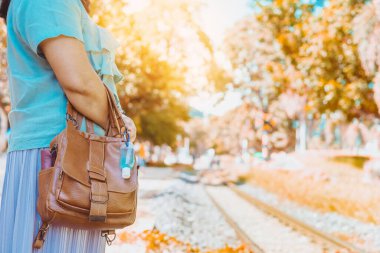 Corona Virüsü 'nü (Covid-19) öldürmek için mini taşınabilir alkol jeli şişesi demiryolu istasyonundaki kadının deri omuz çantasına asıldı. Yeni normal yaşam tarzı. Sağlık hizmeti konsepti. Alkol jeline odaklan