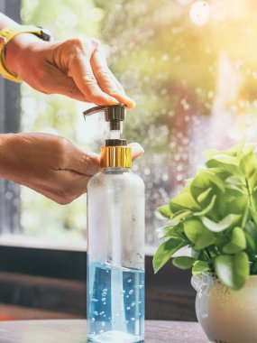 Kadının elleri kahve dükkanına girmeden önce Coronavirus 'un (Covid-19) yayılmasını önlemek için mavi alkol jeli şişesine bastı. Sağlık sigortası konsepti. Yeni normal yaşam tarzı. Seçici odak