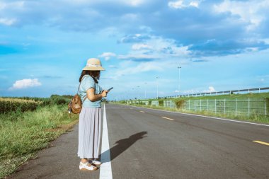 Corona Virüsü 'nü (Covid-19) öldürmek için mini taşınabilir alkol jeli şişesi açık yolda duran bir kadının deri omuz çantasına tutun. Yeni normal yaşam tarzı. Sağlık hizmeti kavramı. Alkol jeline odaklan.