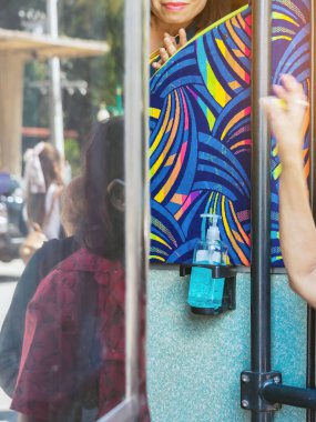 Yolculara hizmet etmek ve Corona Virüsü 'nün (Covid-19) yayılmasını önlemek için çift katlı otobüsün kapısında asılı duran mavi alkol jeli şişesi. Toplu taşımada iyi yolculuklar. Yeni normal yaşam tarzı.